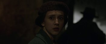 Movie still from “The Nun” (2018), directed by Corin Hardy – A young woman wearing a hat and looking at the camera; Close Up shot, Over the shoulder angle