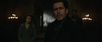 Movie still from “The Nun” (2018), directed by Corin Hardy – A man in a black jacket and a man in a black suit; Medium shot, Over the shoulder angle