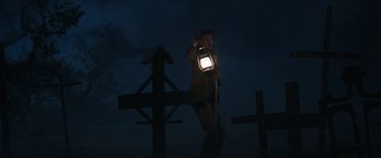 Movie still from “The Nun” (2018), directed by Corin Hardy – A man holding a lantern standing next to two crosses; Wide shot, Low angle