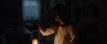 Movie still from “The Nun” (2018), directed by Corin Hardy – A girl in a white dress is holding a lantern; Medium shot, Over the shoulder angle