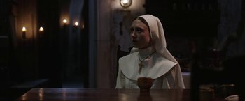 Movie still from “The Nun” (2018), directed by Corin Hardy – A nun sitting at a table with a cup in front of her; Close Up shot, High angle