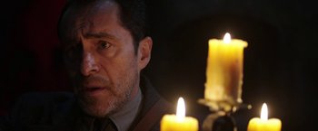 Movie still from “The Nun” (2018), directed by Corin Hardy – A person near a candle; Close Up shot, Over the shoulder angle