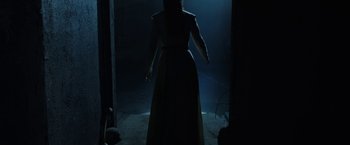 Movie still from “The Nun” (2018), directed by Corin Hardy – A woman standing in the dark in a dark room; Wide shot, Low angle