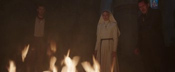 Movie still from “The Nun” (2018), directed by Corin Hardy – A woman dressed as a nun standing in front of a fire pit; Wide shot, High angle