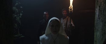 Movie still from “The Nun” (2018), directed by Corin Hardy – A woman wearing a nun's outfit and holding a candle; Medium shot, Low angle