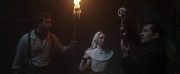Movie still from “The Nun” (2018), directed by Corin Hardy – A woman dressed as a nun is holding a torch; Medium shot, Low angle
