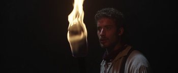 Movie still from “The Nun” (2018), directed by Corin Hardy – A man standing in front of a flame; Close Up shot, Low angle