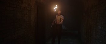 Movie still from “The Nun” (2018), directed by Corin Hardy – A man holding a stick with a fire in it; Wide shot, Low angle