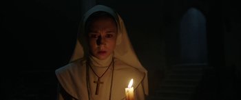 Movie still from “The Nun” (2018), directed by Corin Hardy – A nun with a cross on her head and a candle in the dark; Close Up shot, Low angle