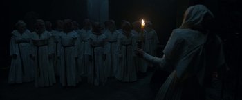 Movie still from “The Nun” (2018), directed by Corin Hardy – A group of people dressed in white holding a candle; Medium shot, High angle