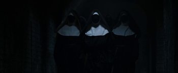 Movie still from “The Nun” (2018), directed by Corin Hardy – A group of people standing next to each other in the dark; Medium shot, High angle