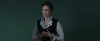 Movie still from “The Nun” (2018), directed by Corin Hardy – A beautiful woman standing in front of a green wall; Medium shot, Over the shoulder angle