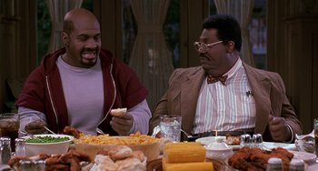 Movie still from “The Nutty Professor” (1996), directed by Tom Shadyac – Two men sitting at a dinner table eating food; Medium shot, High angle