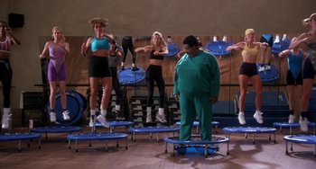 Movie still from “The Nutty Professor” (1996), directed by Tom Shadyac – A group of women are doing exercises on small trampolines in a gym; Wide shot, Low angle