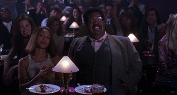 Movie still from “The Nutty Professor” (1996), directed by Tom Shadyac – A group of people sitting at a table with food on it; Medium shot, Low angle
