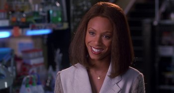Movie still from “The Nutty Professor” (1996), directed by Tom Shadyac – A woman smiling for the camera in a white jacket; Close Up shot, Over the shoulder angle