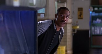 Movie still from “The Nutty Professor” (1996), directed by Tom Shadyac – A man standing in front of a mirror in a room; Close Up shot, Over the shoulder angle