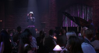 Movie still from “The Nutty Professor” (1996), directed by Tom Shadyac – A man singing into a microphone in front of an audience; Medium shot, Over the shoulder angle