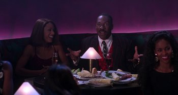 Movie still from “The Nutty Professor” (1996), directed by Tom Shadyac – A man sitting at a table with a plate of food; Medium shot, Over the shoulder angle