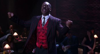 Movie still from “The Nutty Professor” (1996), directed by Tom Shadyac – A man in a suit and tie is singing; Medium shot, Low angle