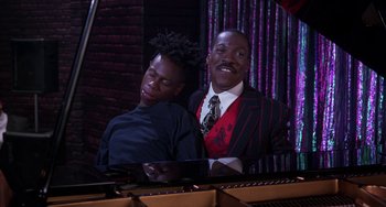 Movie still from “The Nutty Professor” (1996), directed by Tom Shadyac – A man and a boy sitting next to each other at a piano; Medium shot, High angle