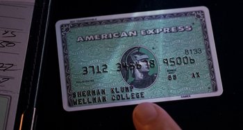 Movie still from “The Nutty Professor” (1996), directed by Tom Shadyac – A hand is holding on to a green american express credit card; Extreme Close Up shot, Overhead angle