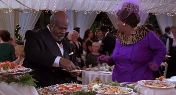 Movie still from “The Nutty Professor” (1996), directed by Tom Shadyac – A man and a woman cutting a sandwich at an event; Medium shot, High angle