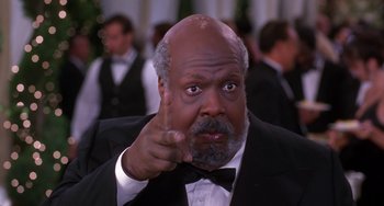 Movie still from “The Nutty Professor” (1996), directed by Tom Shadyac – A man in a suit and bow tie pointing to the camera; Close Up shot, Low angle