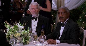 Movie still from “The Nutty Professor” (1996), directed by Tom Shadyac – Two men sitting at a table with champagne glasses; Medium shot, High angle