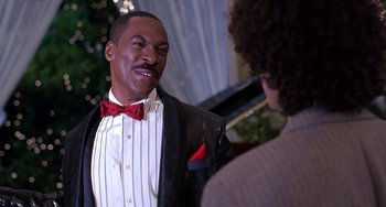 Movie still from “The Nutty Professor” (1996), directed by Tom Shadyac – A man in a suit and bow tie talking to another man in a suit and bow tie; Close Up shot, Over the shoulder angle