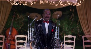 Movie still from “The Nutty Professor” (1996), directed by Tom Shadyac – A man in a shiny black jacket and red bow tie; Medium shot, Low angle