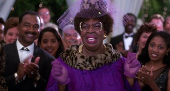 Movie still from “The Nutty Professor” (1996), directed by Tom Shadyac – An older woman in a purple coat and a purple hat; Close Up shot, Low angle