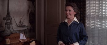 Movie still from “The Omen” (1976), directed by Richard Donner – A woman in a blue shirt smiling for the camera; Medium shot, Over the shoulder angle