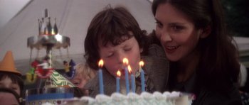 Movie still from “The Omen” (1976), directed by Richard Donner – A woman and a child blow out candles on a birthday cake; Close Up shot, Over the shoulder angle