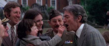 Movie still from “The Omen” (1976), directed by Richard Donner – An older man and a young girl feeding a man a piece of cake; Close Up shot, Over the shoulder angle
