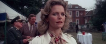 Movie still from “The Omen” (1976), directed by Richard Donner – An older woman wearing a white jacket and a floral neck tie; Close Up shot, Low angle