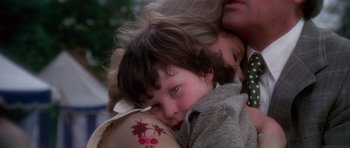 Movie still from “The Omen” (1976), directed by Richard Donner – A young child is held by a woman; Close Up shot, High angle