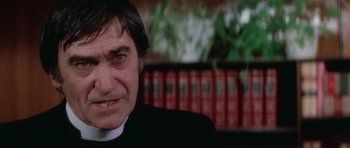 Movie still from “The Omen” (1976), directed by Richard Donner – A person wearing a priest's outfit; Close Up shot, Low angle