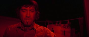 Movie still from “The Omen” (1976), directed by Richard Donner – A man smoking a cigarette in a dark room; Close Up shot, Low angle