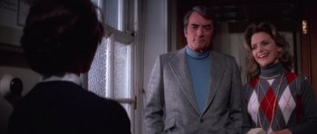Movie still from “The Omen” (1976), directed by Richard Donner – A man wearing a suit and a blue sweater; Medium shot, Over the shoulder angle
