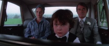 Movie still from “The Omen” (1976), directed by Richard Donner – A woman and a child in a car; Medium shot, High angle