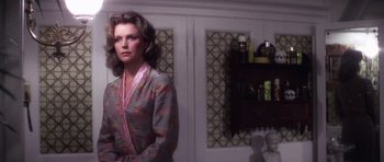 Movie still from “The Omen” (1976), directed by Richard Donner – A woman standing in front of a mirror in a room; Medium shot, Low angle