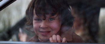 Movie still from “The Omen” (1976), directed by Richard Donner – A little girl looking out a window at the camera; Close Up shot, Low angle