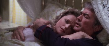 Movie still from “The Omen” (1976), directed by Richard Donner – A woman laying in bed with a man holding her arm; Close Up shot, Overhead angle