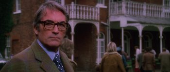 Movie still from “The Omen” (1976), directed by Richard Donner – A man in a suit and tie standing in front of a building; Close Up shot, Low angle