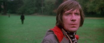 Movie still from “The Omen” (1976), directed by Richard Donner – A person wearing a jacket in a field; Close Up shot, Low angle