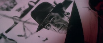 Movie still from “The Omen” (1976), directed by Richard Donner – An older man wearing a black hat looking up at the sky; Extreme Close Up shot, Low angle