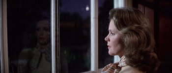 Movie still from “The Omen” (1976), directed by Richard Donner – A woman sitting in front of a window at night; Close Up shot, Over the shoulder angle