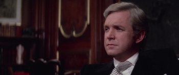 Movie still from “The Omen” (1976), directed by Richard Donner – A person wearing a suit and tie; Close Up shot, Over the shoulder angle