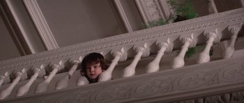 Movie still from “The Omen” (1976), directed by Richard Donner – A young girl looking over the railing of a balcony; Medium shot, Low angle